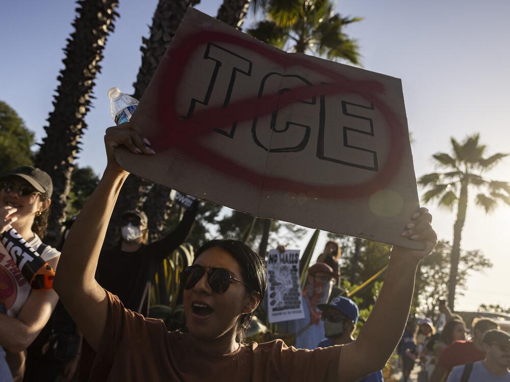A demonstrator holds up a sign as they protest in front of the main entrance of Dodger Stadium on Thursday.