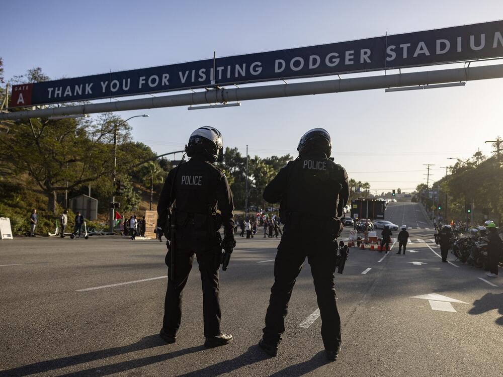 Police officers stand guard as they close the gate of the main entrance of Dodger Stadium on Thursday.
