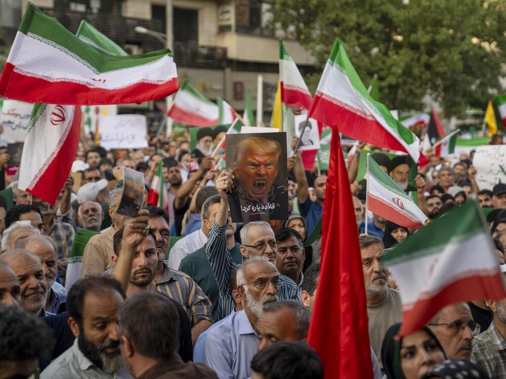 Iranian protesters chant slogans and one holds a poster with a vampire-like illustration of President Trump in Tehran's Revolution Square on Sunday to protest the U.S. attacks on nuclear sites in Iran.