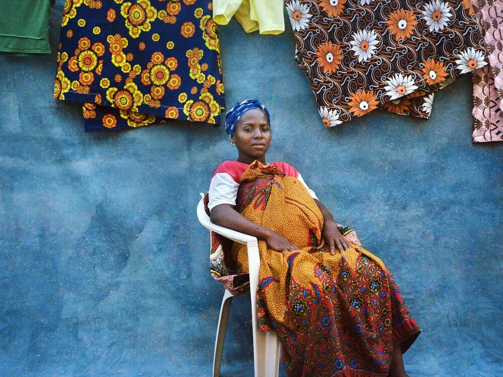 A portrait of Julie Moanariziky, who had contracted female genital schistosomiasis. The photographer posed her in front of a canvas painted blue, to symbolize water, with white dots representing the parasitic worms that spread the infection.