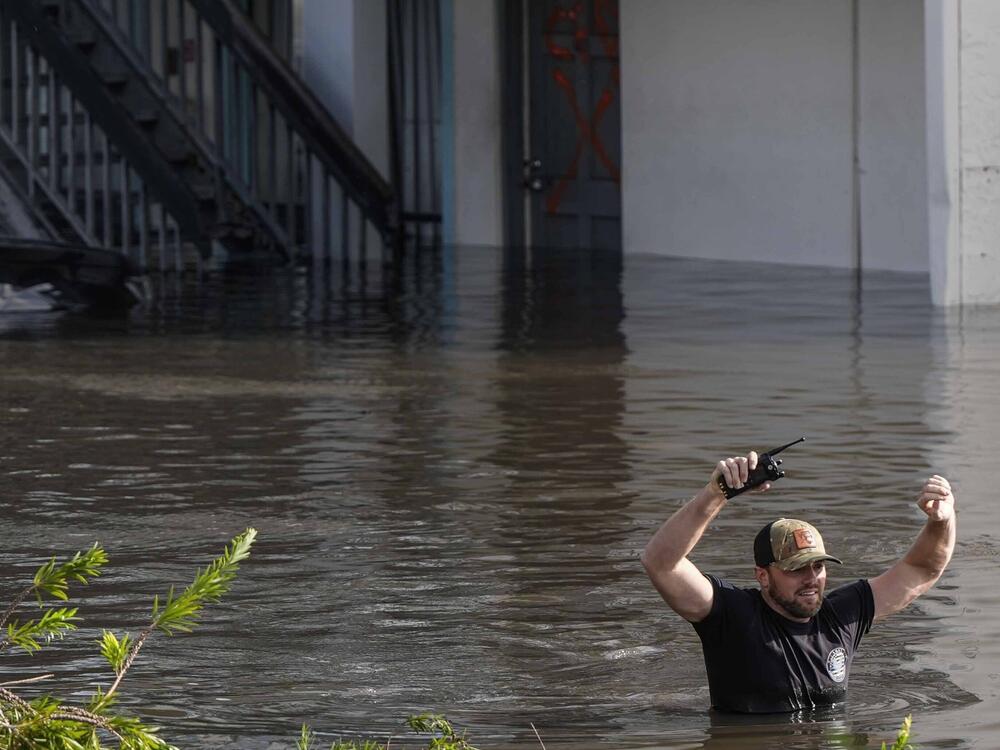 A water rescue team member walks through flood waters at an apartment complex in Clearwater, Fla.