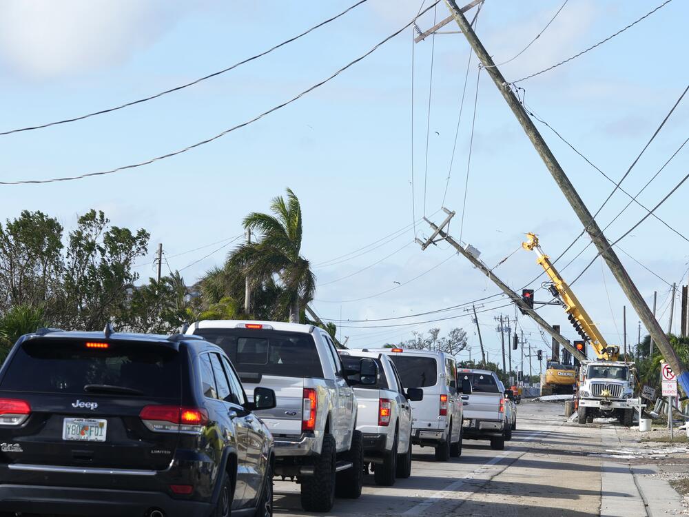 Cars move slowly after Hurricane Milton damaged power lines, in Matlacha, Fla.
