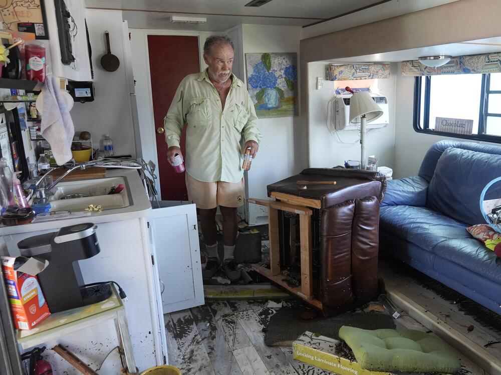 Fred Hill gets a few drinks from his destroyed home after it was hit by a tornado and flooding caused by Hurricane Milton, Thursday, in Matlacha, Fla.
