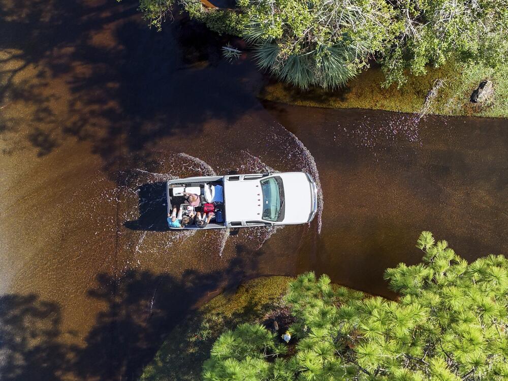 Two couples who evacuated get a ride back to their home through flooding after Hurricane Milton hit the region, Thursday, in Palm Harbor, Fla.