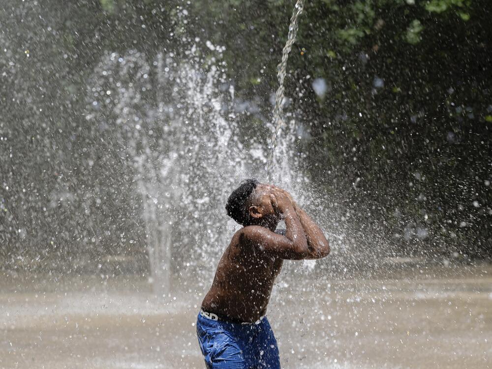 A child covers his face while a stream of water pours down at Waterfront Park on Sunday, June 22, 2025, in Louisville, Ky.