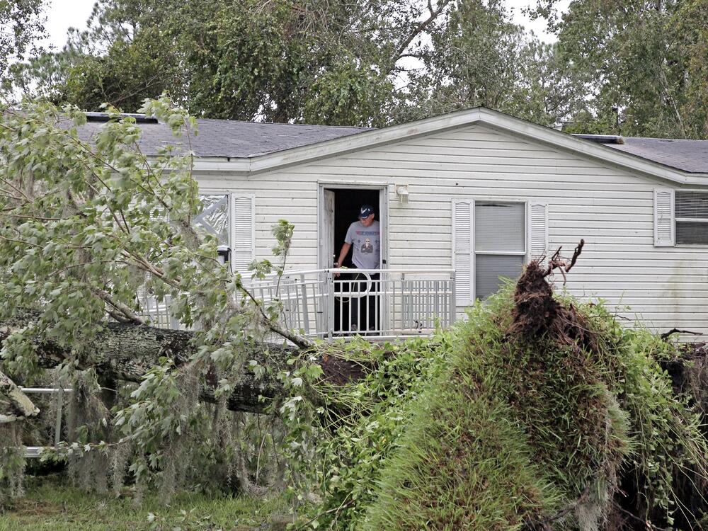 A local resident observes a tree which fell on his house in Kissimmee, Fla. Hurricane Milton tore a coast-to-coast path of destruction across the US state of Florida, whipping up a spate of deadly tornadoes that left at least four people dead, but avoiding the catastrophic devastation officials had feared.