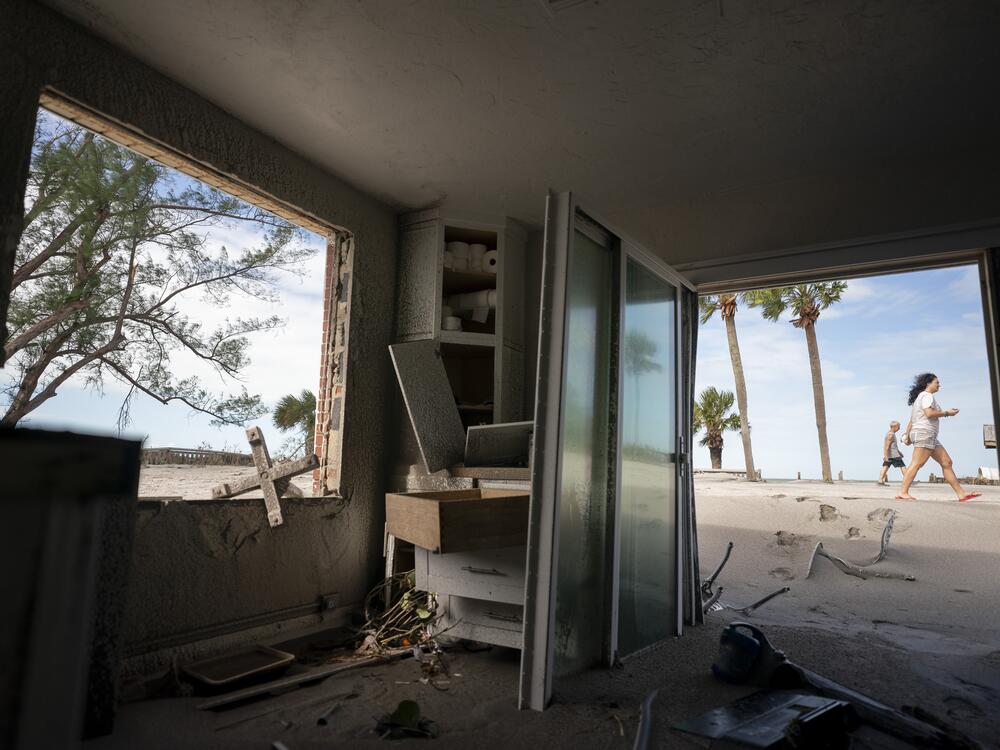 People walk near storm damaged beachside property in Venice, Florida on Thursday.
