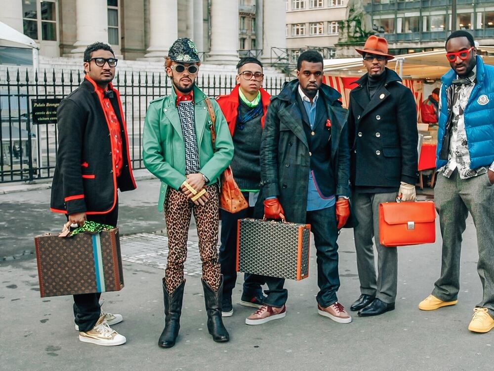 Virgil Abloh (far right) with his then-employer Kanye West (center, holding briefcase) at Paris Fashion Week in 2009.