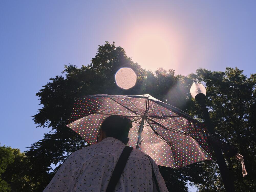 With temperatures hovering near 100 degrees, a woman protects herself from the sun while walking through Boston Common on Tuesday.