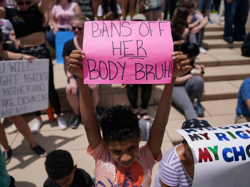 A young boy holds up a sign reading 
