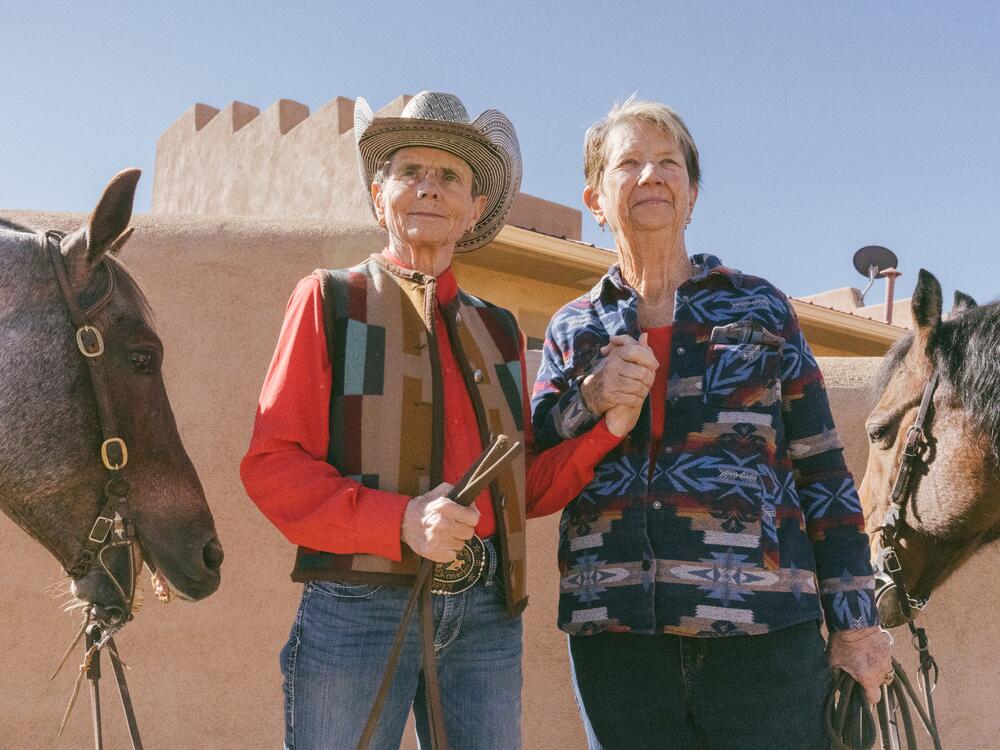 Terry Berg (left) and Helen Newton hold hands next to their horses at their home in Santa Fe, N.M.