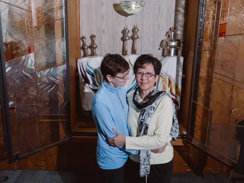 Davi Cheng (right) and Bracha Yael stand in front of the Torah ark at Temple Beth Chayim Chadashim in Los Angeles. Davi helped design the stained glass throughout the synagogue.