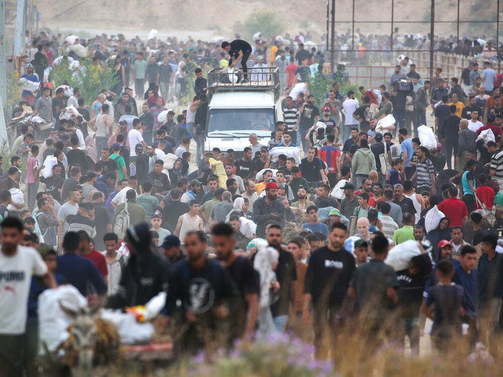 People carry relief supplies from the Gaza Humanitarian Foundation (GHF), a private U.S.-backed aid group that has bypassed the long-standing United Nations-led system in the territory, as displaced Palestinians return from an aid distribution center in the central Gaza Strip, on June 8.