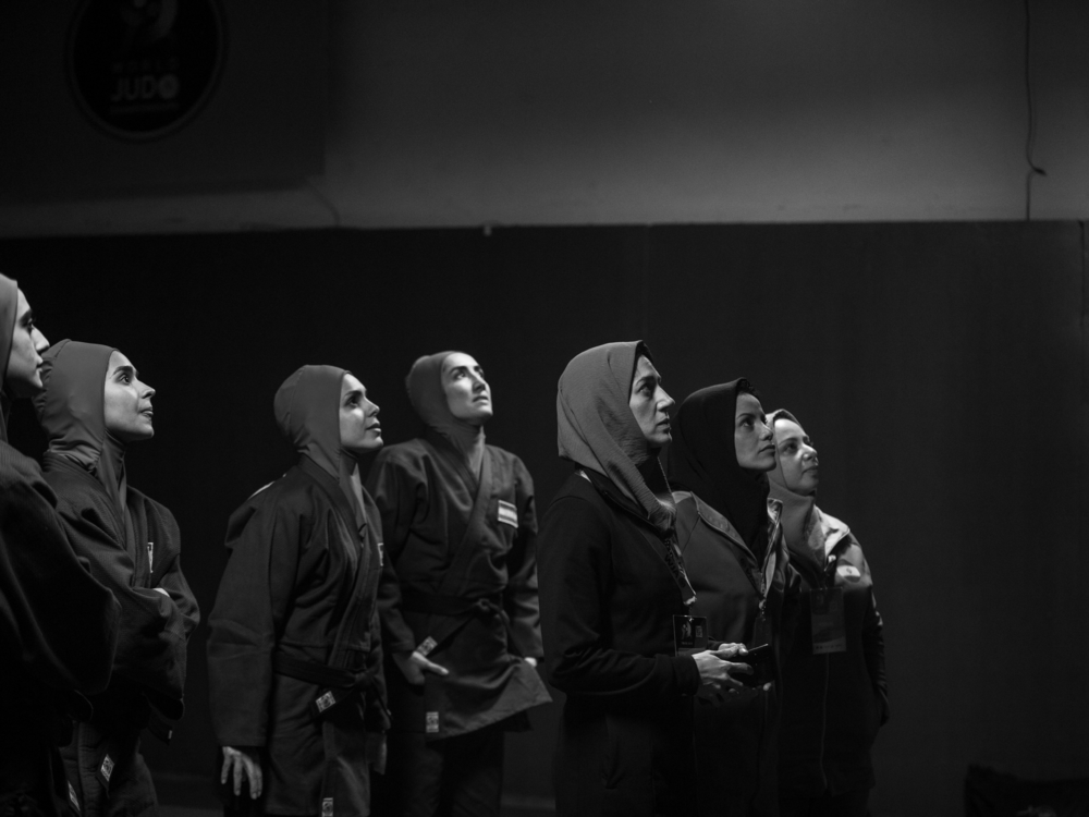Coach Maryam Ghanbari, played by <em>Tatami </em>co-director Zar Amir (center), watches the screen with other judo athletes as Leila's match begins.