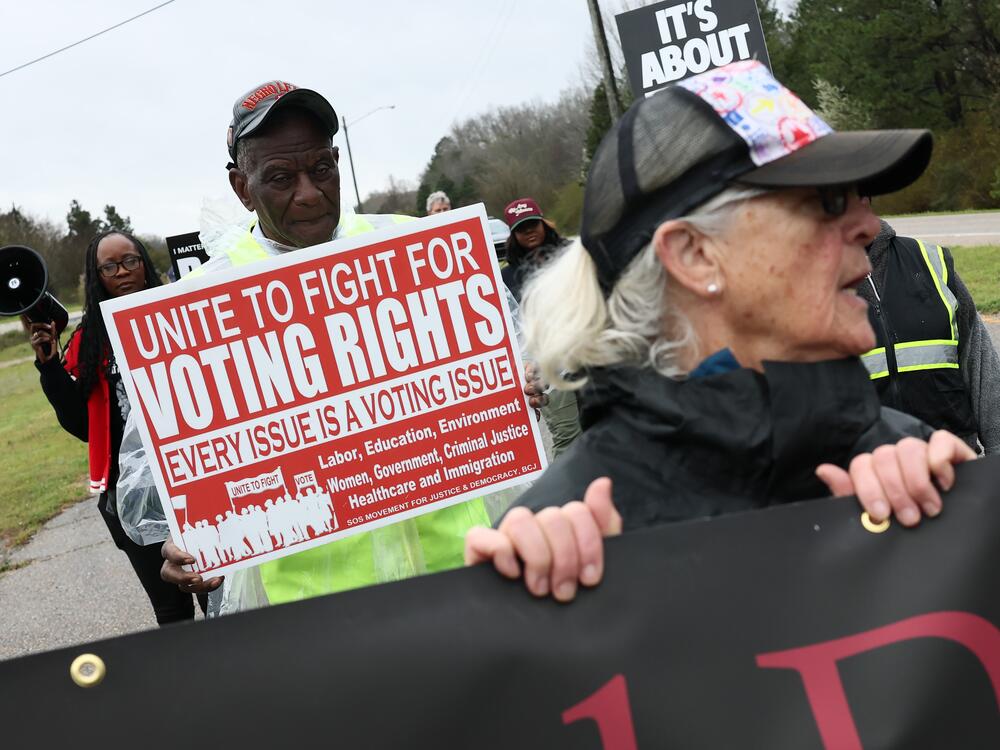 Demonstrators walk in Selma, Ala., in March with a sign saying 