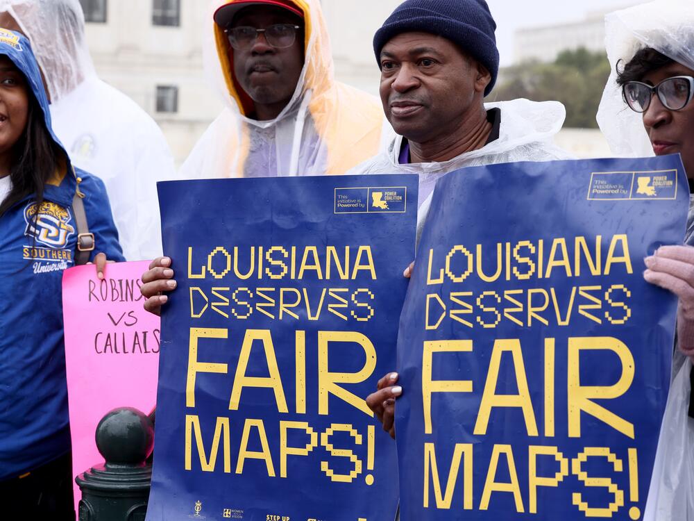 Civil rights advocates hold signs saying 