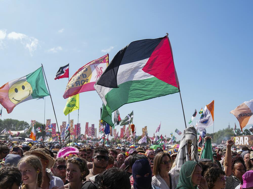 The flag of Palestine is waved in a crowd of festivalgoers at the hip hop trio Kneecap's performance during the Glastonbury Festival in Worthy Farm, Somerset, England, Saturday, June 28, 2025.