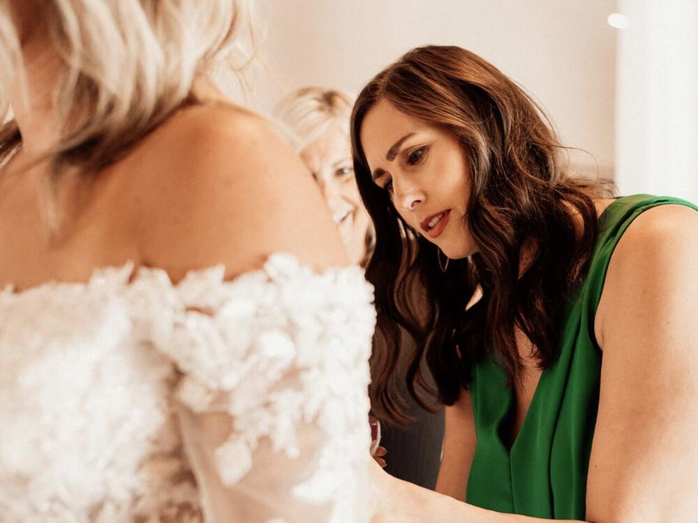 Claire Landgraf helps a bride try on a dress at her shop Finery Bridal Chic in Rochester, Minn.