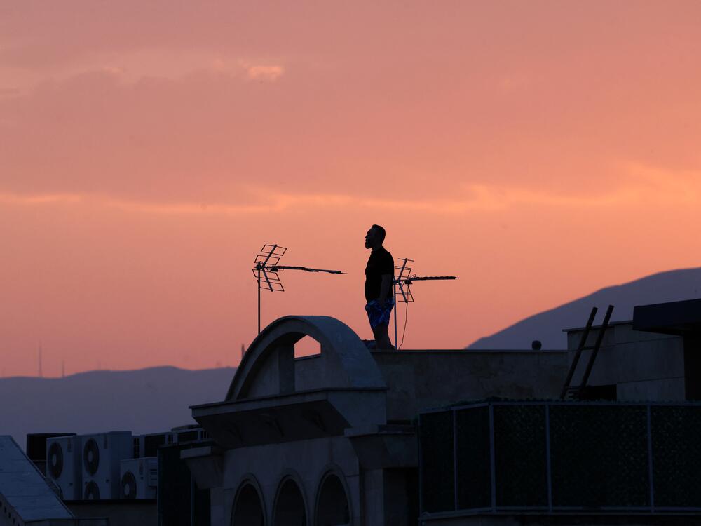 A man stands on the roof of a building while watching the horizon in Tehran on June 16. Iran's state broadcaster was briefly knocked off the air by an Israeli strike and explosions rang out across Tehran that day.