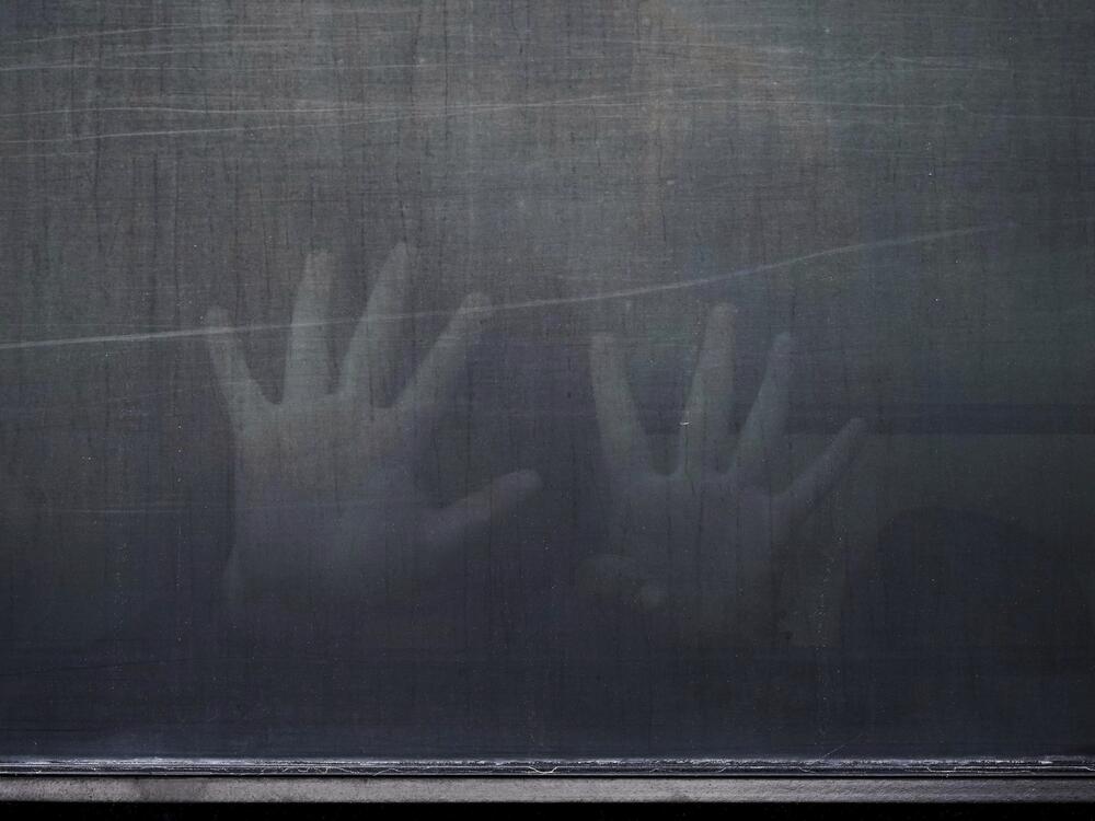 A woman from Peru signals through the barred and tinted windows of a bus after she was detained following an appearance at immigration court on June 23 in San Antonio.