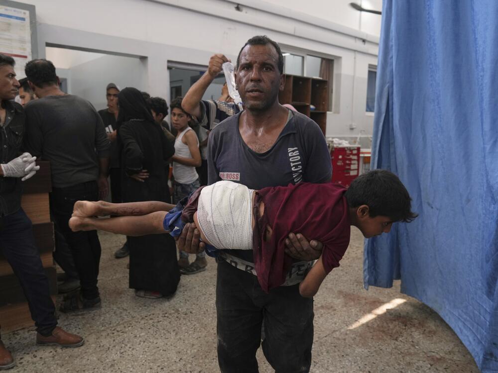A man carries a child, who was wounded in an Israeli strike, after being treated in the Shifa Hospital, Gaza City on Monday.