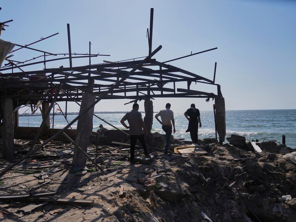 Palestinians walk in what was a cafe after it was damaged by an Israeli strike in Gaza City on Monday.