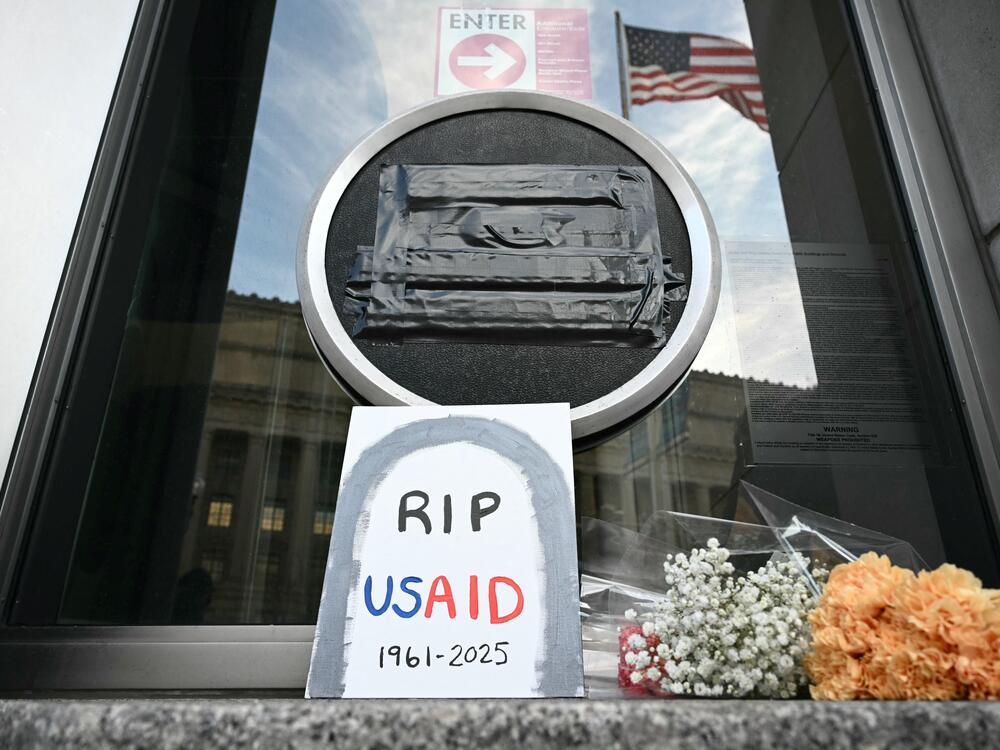 Tributes are placed beneath the covered seal of the United States Agency for International Development (USAID) at their headquarters in Washington, D.C., on February 7, the day that President Donald Trump called for the agency to be shuttered. July 1 marks the agency's official demise.