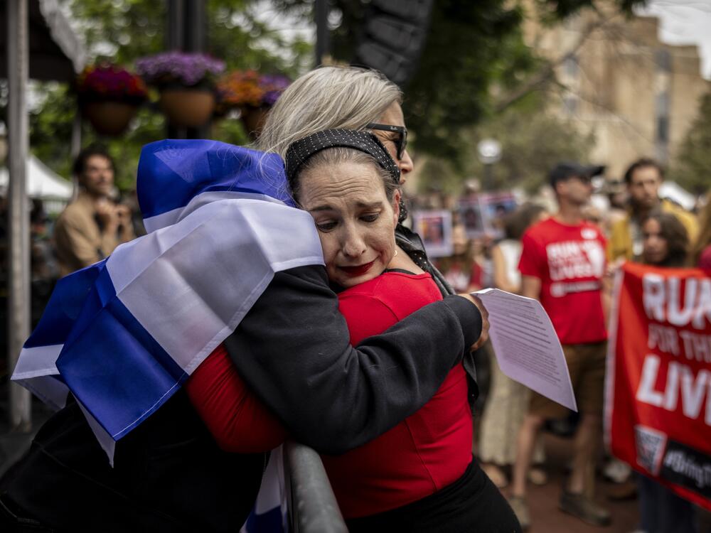 Two members of an organization dedicated to showing solidarity with hostages held in Gaza embrace at a vigil, one week after an antisemitic attack on the group in Boulder, Colo.