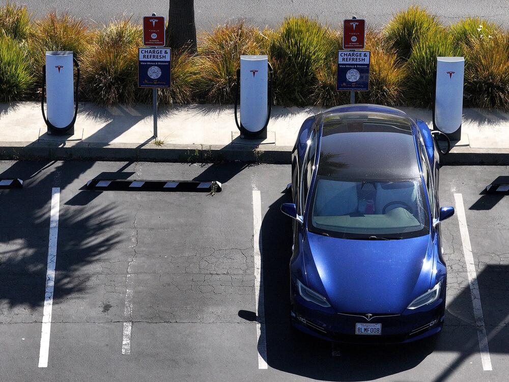 An electric vehicle sits parked at a Tesla charging station in Sausalito, Calif., in June. The tax and spending package under consideration in the Senate could eliminate federal tax credits for buying and purchasing an EV at the end of September — even sooner than a House version of the same bill proposes.