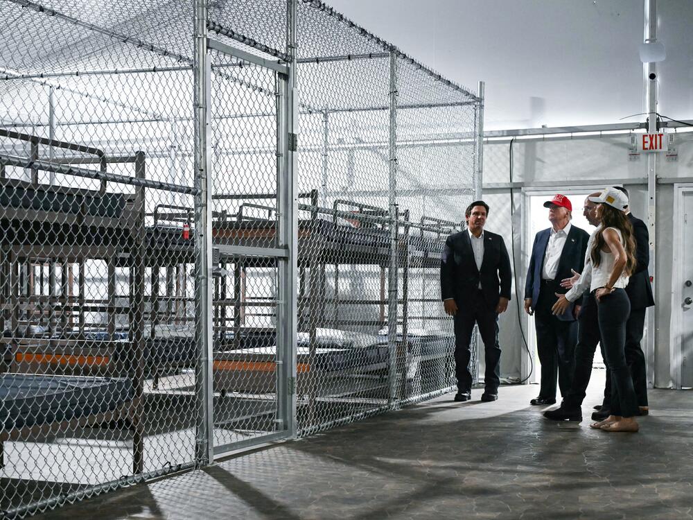 President Donald Trump, along with officials including Florida Gov. Ron DeSantis and Homeland Security Secretary Kristi Noem, tour the new migrant detention facility at the Dade-Collier Training and Transition Airport in Ochopee, Fla., on Tuesday.