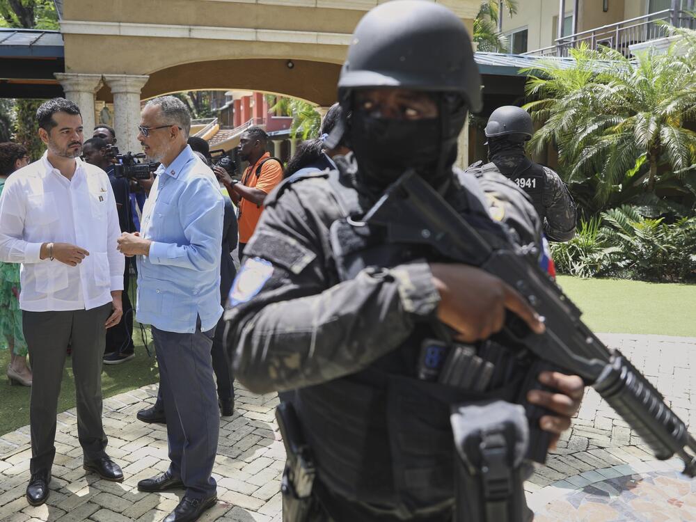 Security guards stand watch as Haiti's Prime Minister Alix Didier Fils-Aime, center, talks with the Mexico's Charge d'Affaires Jesus Cisneros after attending an event marking one year since the start of the Multinational Security Support Mission in Port-au-Prince, Haiti on Thursday.