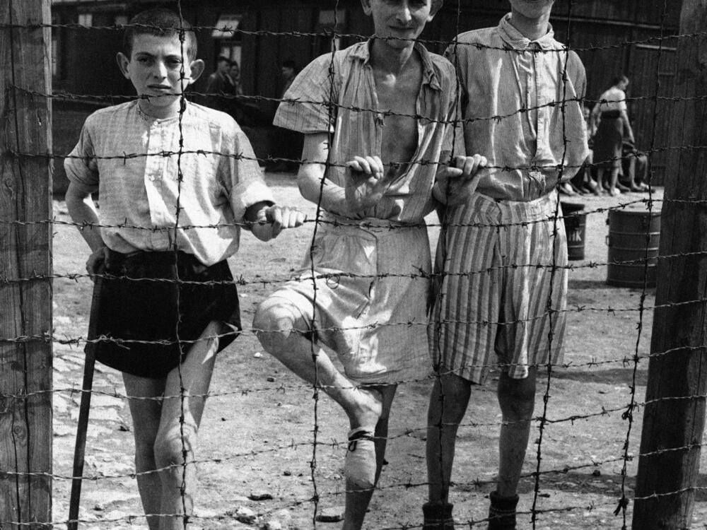Young, emaciated prisoners stand inside the barbed wire of the Buchenwald concentration camp on April 19, 1945, shortly after the U.S. army liberated the camp from the Nazis.