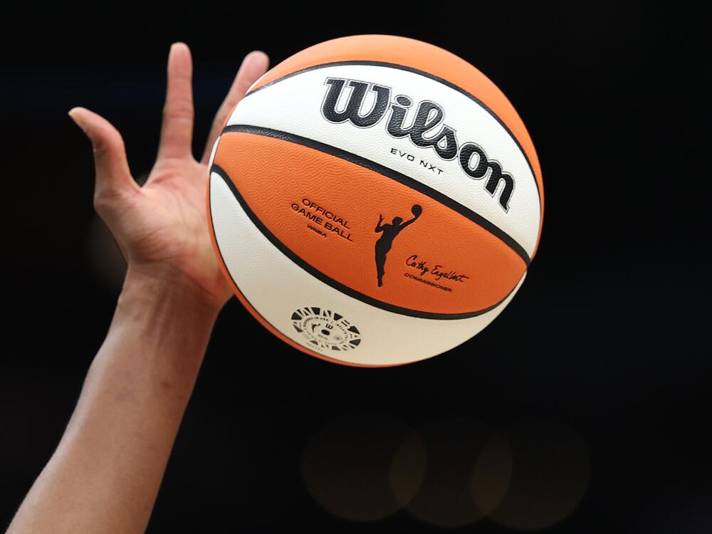 The WNBA logo on the ball is seen as it is tipped during the game between the Seattle Storm and the Las Vegas Aces last year in Seattle, Wash. The WNBA has announced it's expanding to a record 18 teams — adding three new franchises: Cleveland, Detroit and Philadelphia.