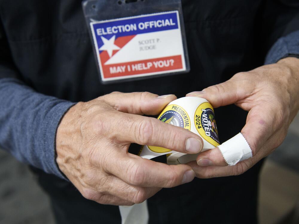 In this file photo, a poll worker rolls up stickers while working inside a FEMA tent used as a voting site on Nov. 5, 2024,  in Morganton, N.C.