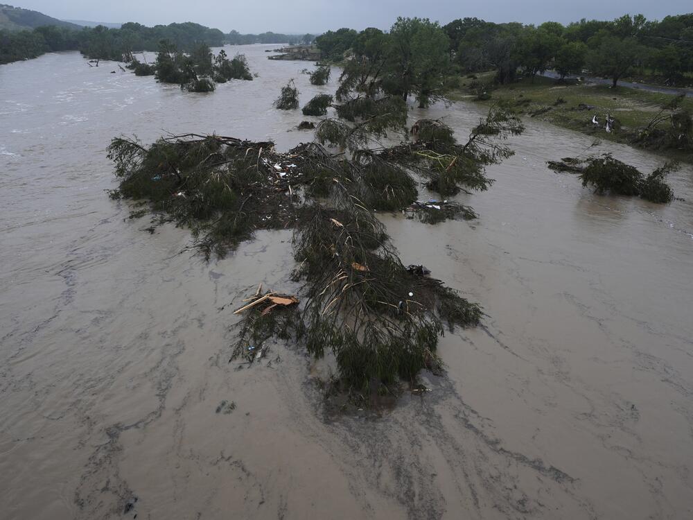 A raging Guadalupe River leaves fallen trees and debris in its wake in Kerrville, Texas.