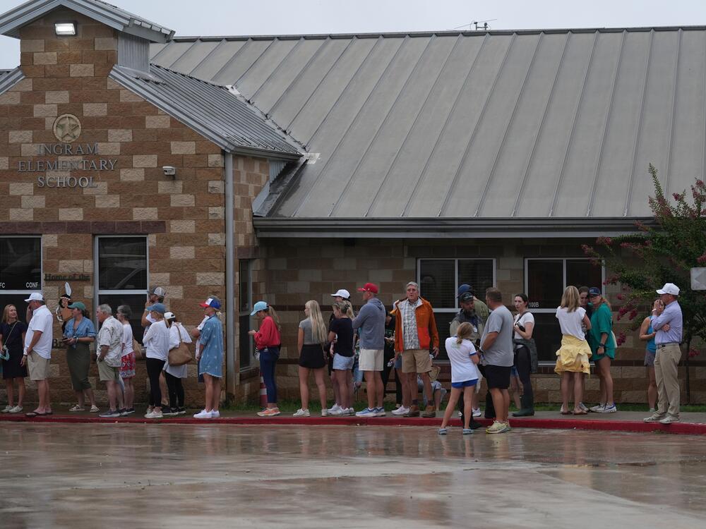 Families line up at a reunification center after flash flooding it the area in Ingram, Texas.