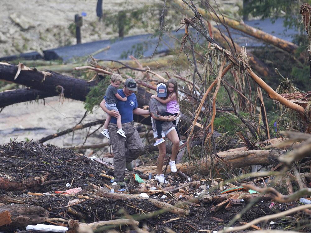 People climb over debris on a bridge atop the Guadalupe River after a flash flood swept through the area Saturday, July 5, 2025, in Ingram, Texas