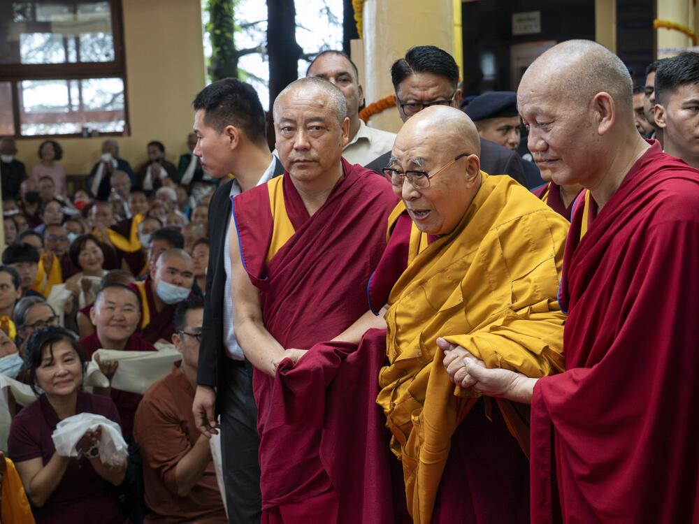 Tibetan spiritual leader the Dalai Lama, in yellow robe, is helped by attendant monks as he arrives to preside over an event during which Tibetan exiles prayed for his longevity, a day before his 90th birthday, in Dharamshala, India, Saturday, July 5, 2025.