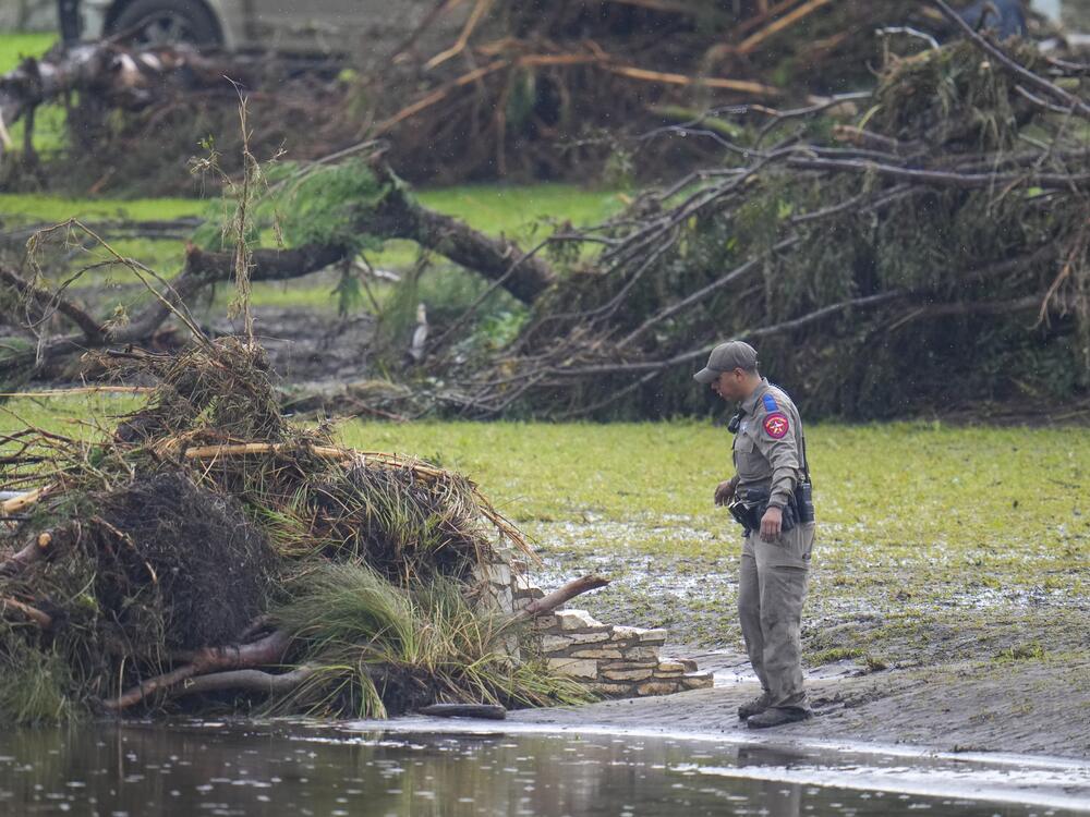 A Texas Department of Public Safety official inspects debris on the waterfront at Camp Mystic along the banks of the Guadalupe River after a flash flood swept through the area Sunday, July 6, in Hunt, Texas.