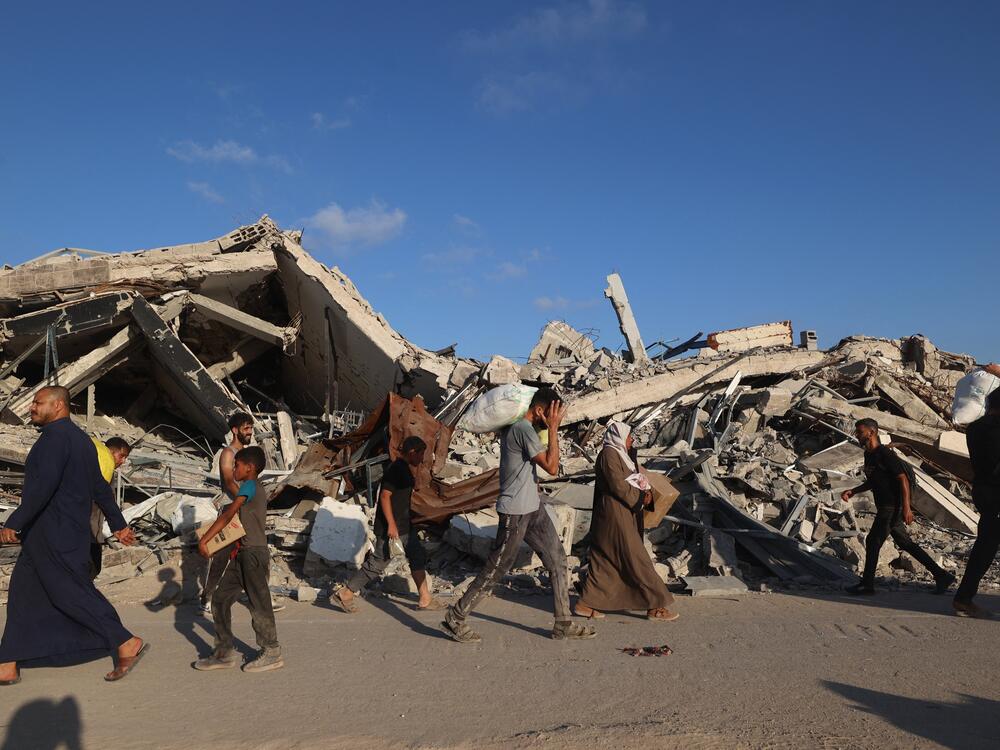 People, some carrying aid parcels, walk along the Salah al-Din road near the Nuseirat refugee camp in the central Gaza Strip, used by food-seeking Palestinians to reach an aid distribution point set up by the privately run Gaza Humanitarian Foundation.
