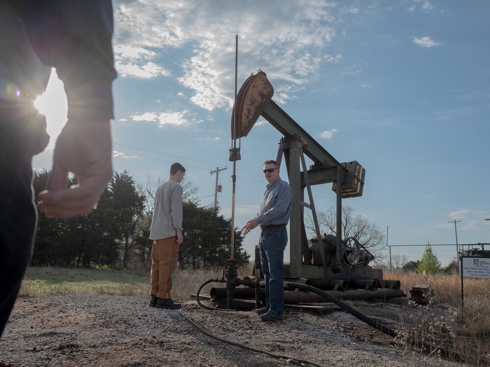 Carter Arthur (left) and Dan Arthur examine an active pumpjack in Sperry, Okla., on March 20, 2024.