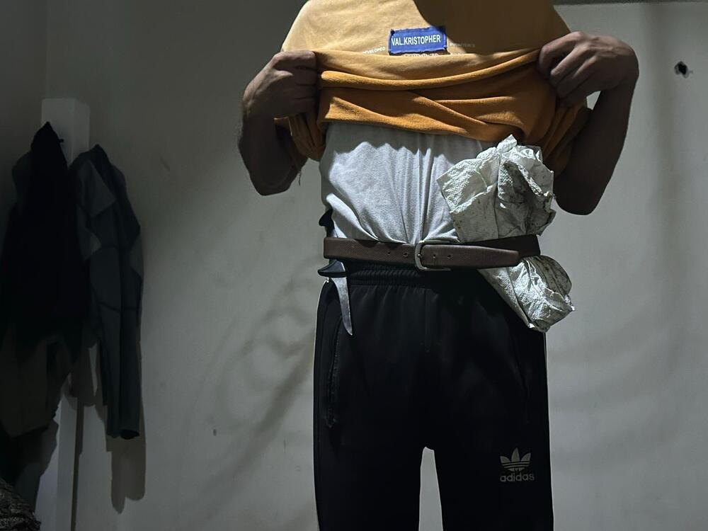 A Palestinian tucks an empty sack under his belt to collect food at a Gaza Humanitarian Foundation food site, and carries a knife to protect from looters near the site, as hunger spreads lawlessness throughout Gaza.
