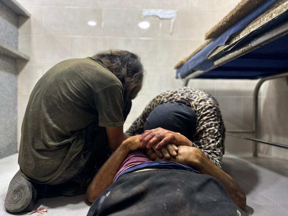 A mother, with her son, grieves over the body of her husband, who was shot by the Israeli military as he approached a Gaza Humanitarian Foundation food distribution center, at the Al-Awda Hospital in northern Gaza on June 24, 2025.