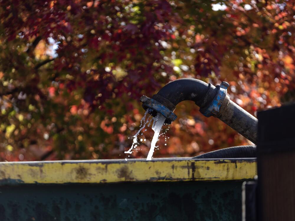 Water flows out of a pipe as a team works to remove an old plug from an orphan gas well in Ashland, Ohio, on October 24, 2024.