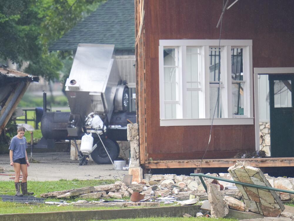 A person looks at damage to the main building at Camp Mystic, along the banks of the Guadalupe River in Texas. A flash flood swept through the area in the early hours of July 4, 2025. Climate change is making heavy rain more common, leading to more flood risk in much of the U.S.