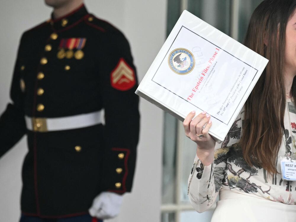 Unidentified people carrying binders bearing the seal of the US Justice Department reading 