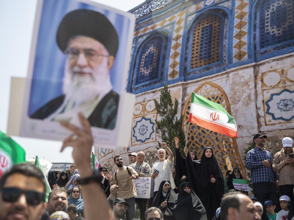 Demonstrators wave Iranian flags as one holds up a poster of Iran's Supreme Leader Ayatollah Ali Khamenei during a protest against Israeli attacks on Iran, after the Friday prayer ceremonies on June 20, 2025 in central Tehran, Iran.