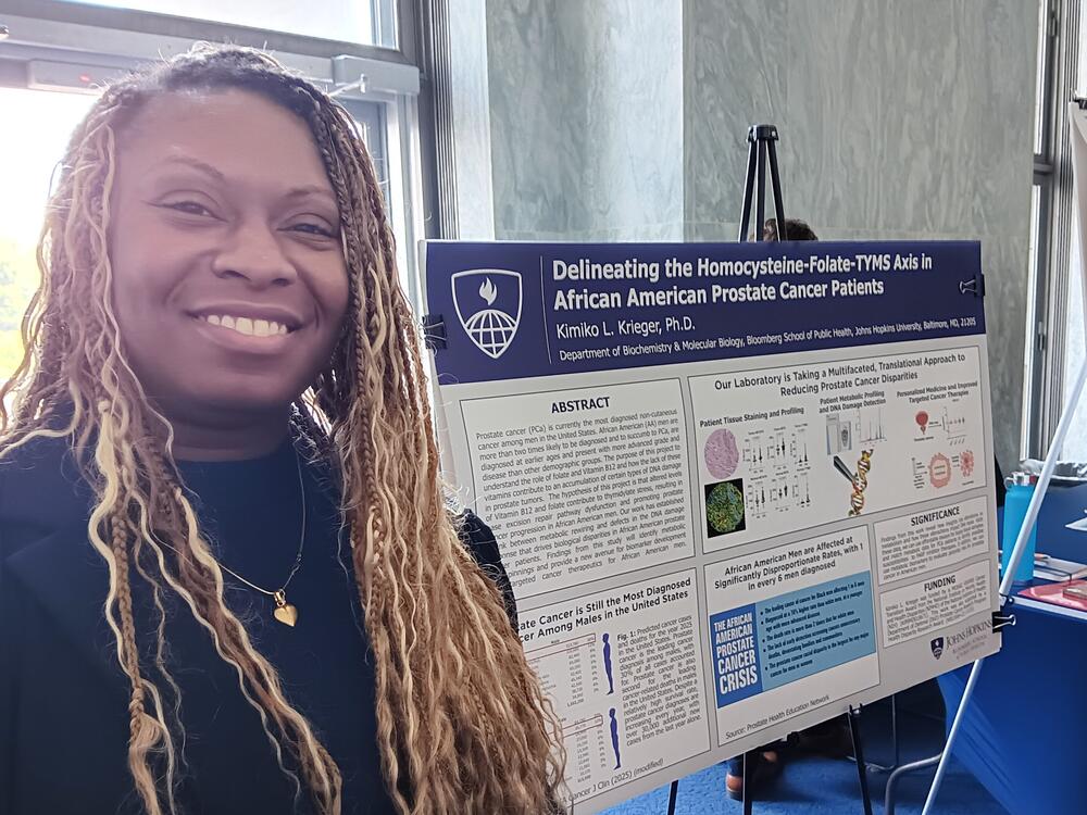 Kimiko Krieger, an assistant professor of biochemistry and molecular biology at the Bloomberg School for Public Health at Johns Hopkins University, stands before a poster describing her research that lost federal funding.