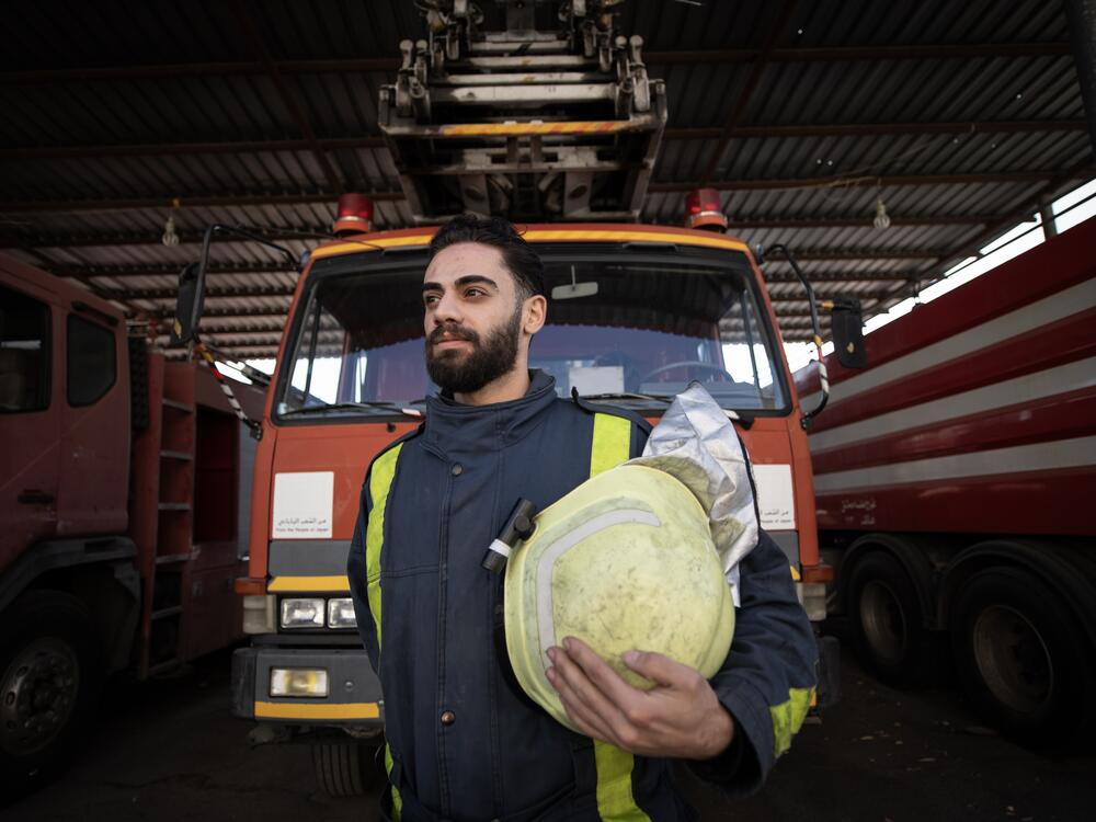 Mohammed Khdeir poses for a portrait in front of a firetruck.