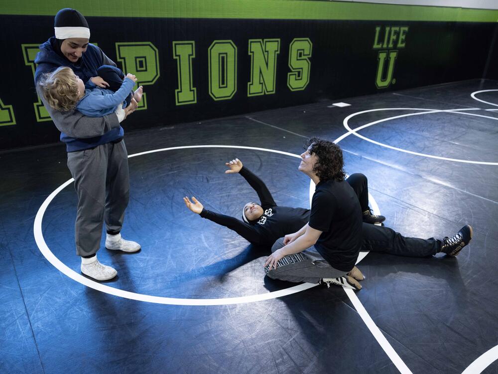 Jamilah McBryde holds her coach's son while teammate Megan Stottsberry and sister Latifah watch.